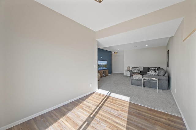 carpeted living area featuring baseboards and wood finished floors