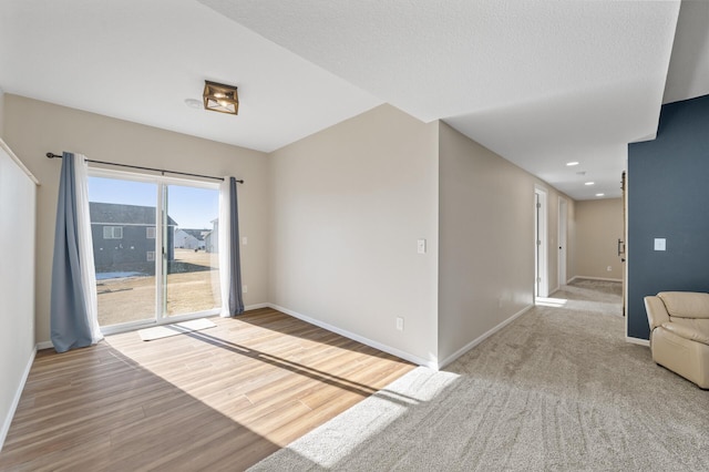 unfurnished room featuring a textured ceiling, baseboards, and wood finished floors