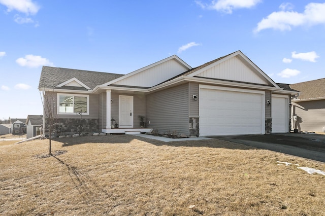 single story home with a garage, stone siding, and aphalt driveway