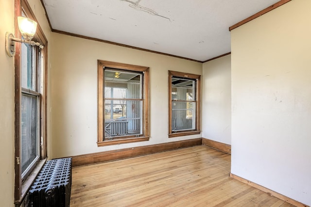 empty room with light hardwood / wood-style flooring and crown molding