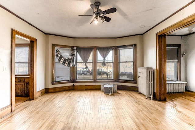 interior space with ceiling fan, light wood-type flooring, radiator heating unit, and a textured ceiling