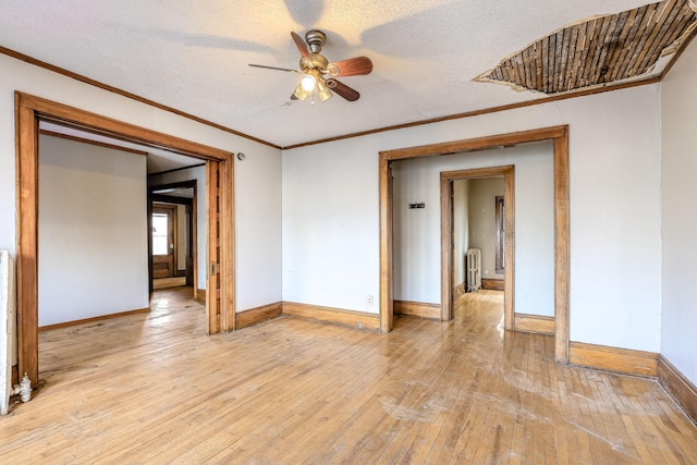 unfurnished room with radiator, ceiling fan, light wood-type flooring, a textured ceiling, and ornamental molding