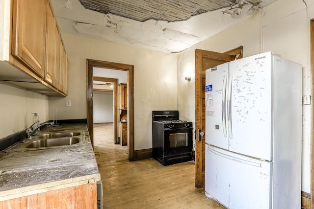 kitchen featuring white refrigerator, sink, black gas range oven, and light hardwood / wood-style flooring