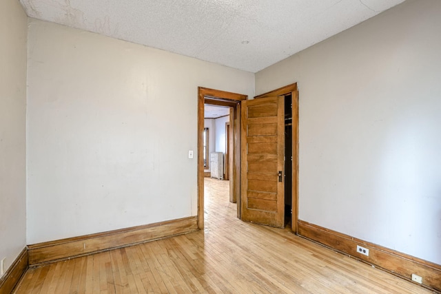 spare room featuring radiator, light hardwood / wood-style floors, and a textured ceiling