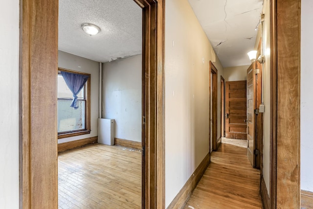 hall featuring light hardwood / wood-style floors and a textured ceiling