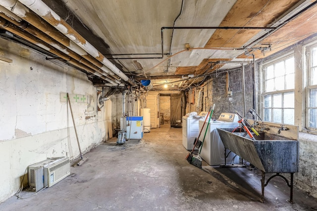 basement featuring washing machine and clothes dryer, sink, and water heater