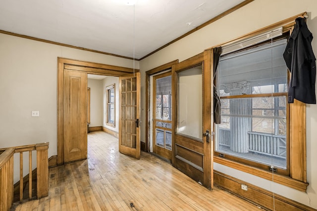 empty room featuring a wealth of natural light, french doors, ornamental molding, and light wood-type flooring