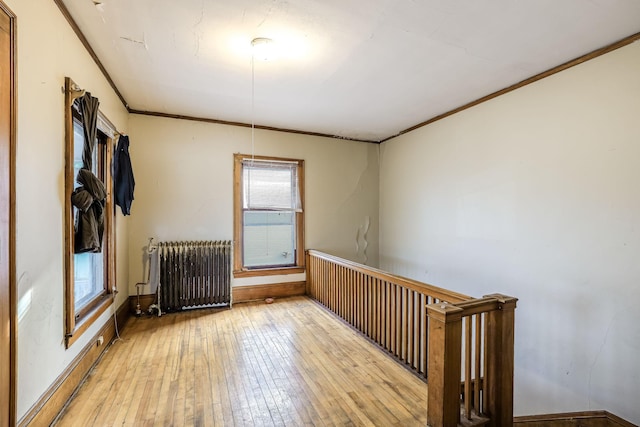 unfurnished room with light wood-type flooring, ornamental molding, and radiator