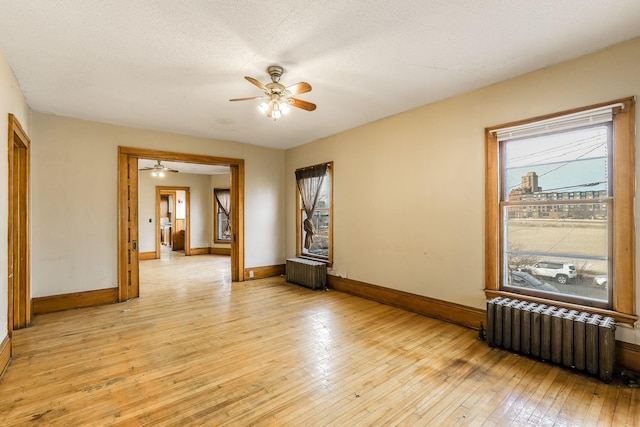 unfurnished room with radiator heating unit, light hardwood / wood-style floors, and a healthy amount of sunlight