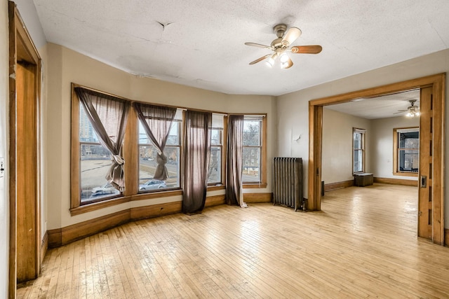 unfurnished room with ceiling fan, light wood-type flooring, and radiator