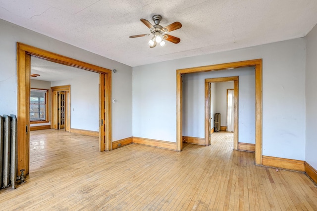 unfurnished room with ceiling fan, light hardwood / wood-style floors, and a textured ceiling