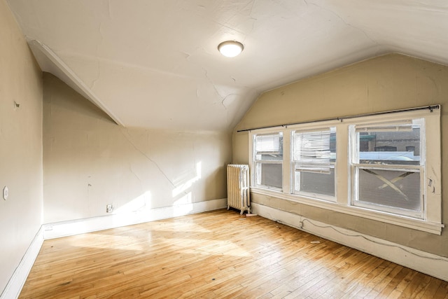 bonus room featuring light wood-type flooring, vaulted ceiling, and radiator