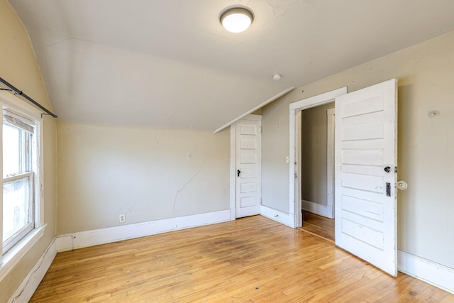 bonus room with light wood-type flooring and vaulted ceiling