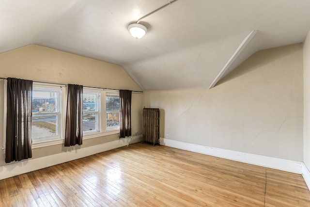 bonus room featuring radiator heating unit, hardwood / wood-style floors, and vaulted ceiling