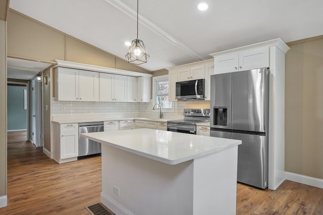 kitchen featuring backsplash, white cabinets, stainless steel appliances, and a kitchen island