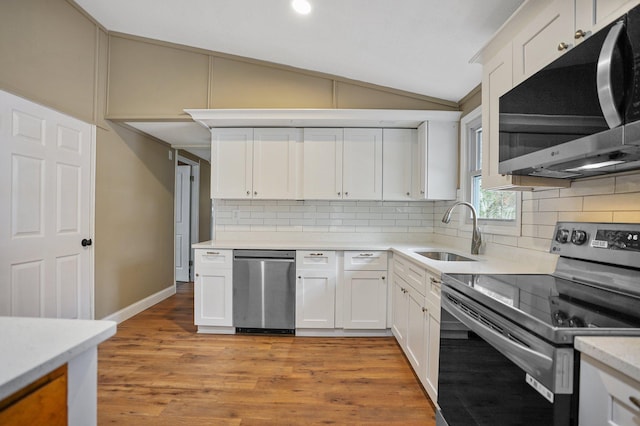 kitchen featuring sink, vaulted ceiling, light wood-type flooring, white cabinetry, and stainless steel appliances