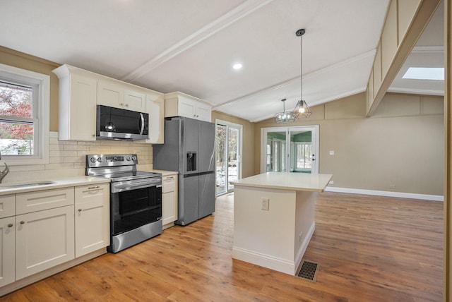 kitchen with appliances with stainless steel finishes, light wood-type flooring, backsplash, vaulted ceiling with beams, and white cabinetry