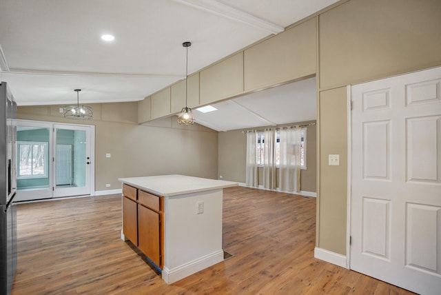 kitchen with lofted ceiling with beams, hardwood / wood-style flooring, a chandelier, a kitchen island, and hanging light fixtures