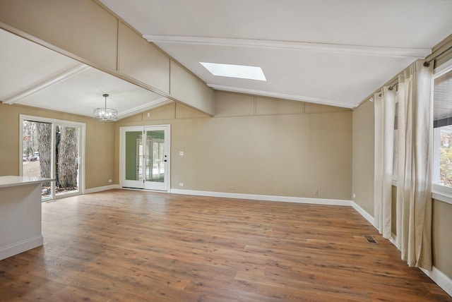 interior space with a chandelier, hardwood / wood-style floors, lofted ceiling with skylight, and a healthy amount of sunlight