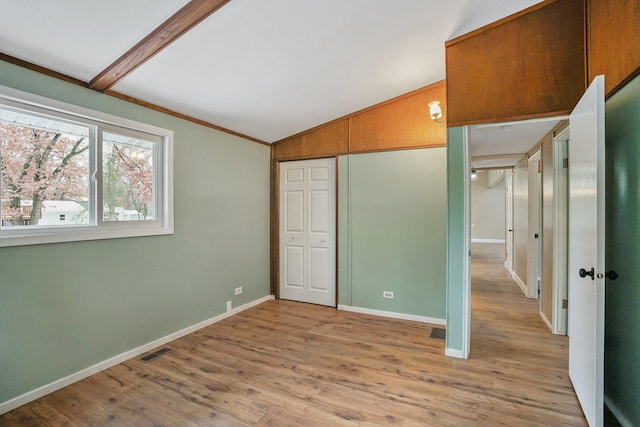 unfurnished bedroom featuring lofted ceiling with beams, light hardwood / wood-style floors, and a closet