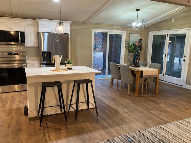 kitchen featuring white cabinetry, a kitchen island, stainless steel appliances, and decorative light fixtures