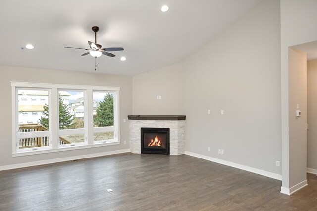 unfurnished living room featuring dark hardwood / wood-style floors, a stone fireplace, and ceiling fan