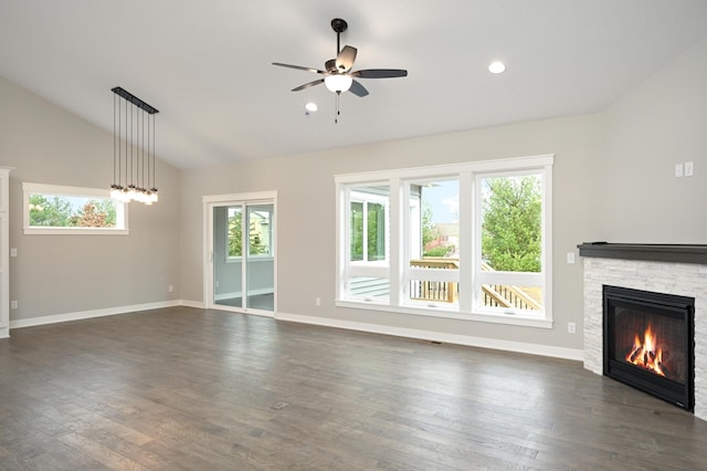 unfurnished living room featuring ceiling fan, a stone fireplace, a wealth of natural light, and vaulted ceiling