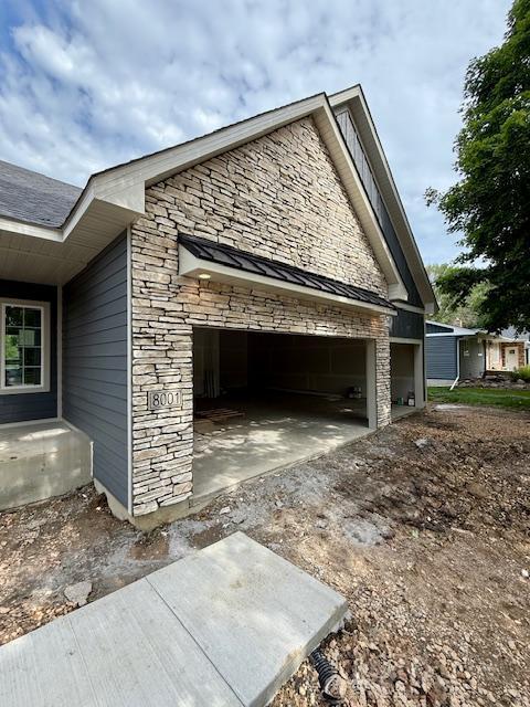 8001 Petunia St, Victoria, MN 55386 - view of property exterior with stone siding, driveway, and an attached garage