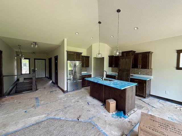 8001 Petunia St, Victoria, MN 55386 - kitchen with stainless steel fridge, dark brown cabinets, a center island with sink, decorative backsplash, and lofted ceiling