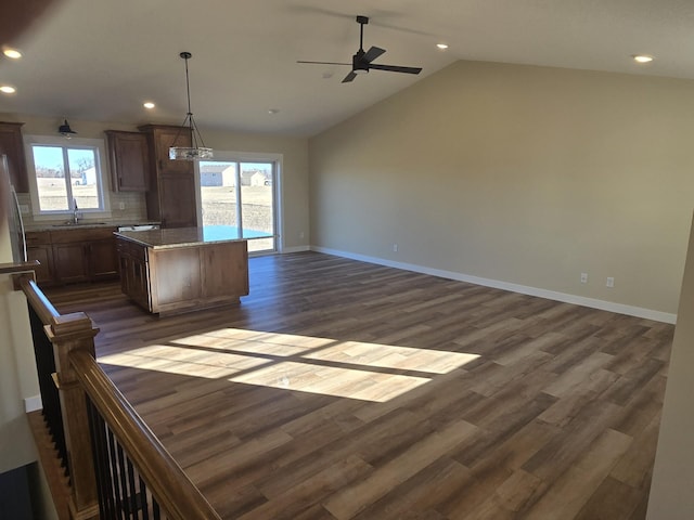 kitchen featuring lofted ceiling, sink, hanging light fixtures, ceiling fan, and a kitchen island