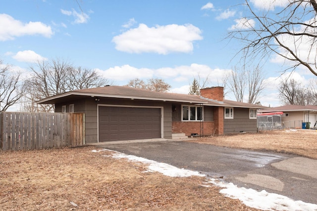 single story home featuring a garage, fence, a chimney, and aphalt driveway