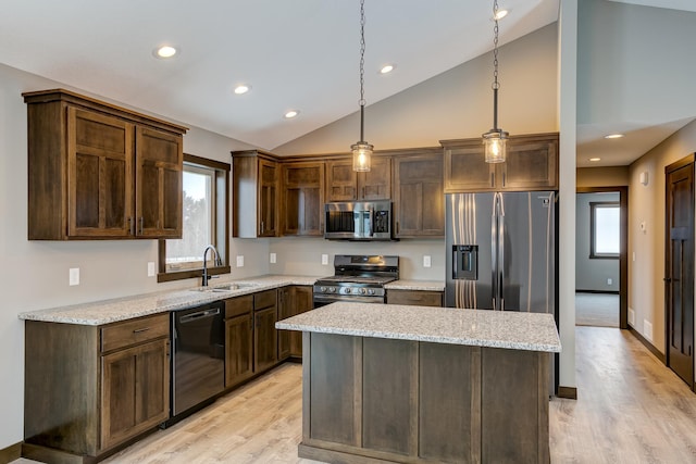 kitchen featuring appliances with stainless steel finishes, light stone counters, vaulted ceiling, pendant lighting, and a kitchen island