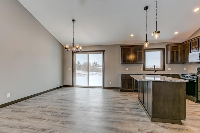 kitchen with dark brown cabinetry, a center island, black range oven, and pendant lighting