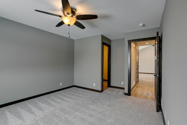 unfurnished bedroom featuring ceiling fan, light colored carpet, and a textured ceiling