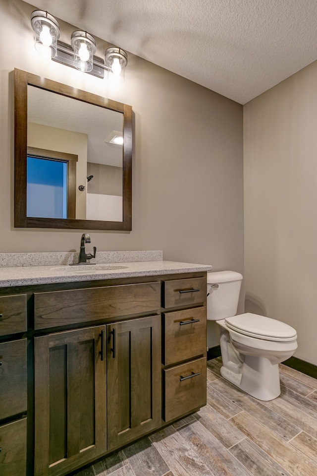 bathroom featuring vanity, a textured ceiling, and toilet