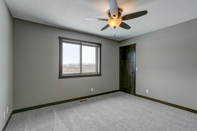 carpeted spare room featuring a textured ceiling and ceiling fan