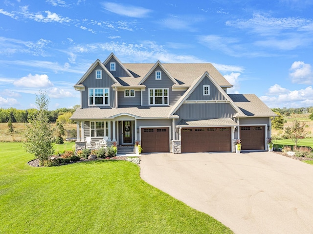 craftsman house with covered porch, a garage, and a front lawn