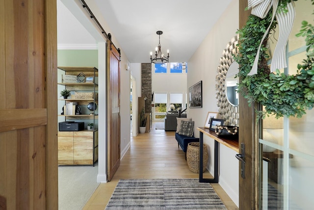 hall featuring a barn door, light hardwood / wood-style flooring, and a notable chandelier