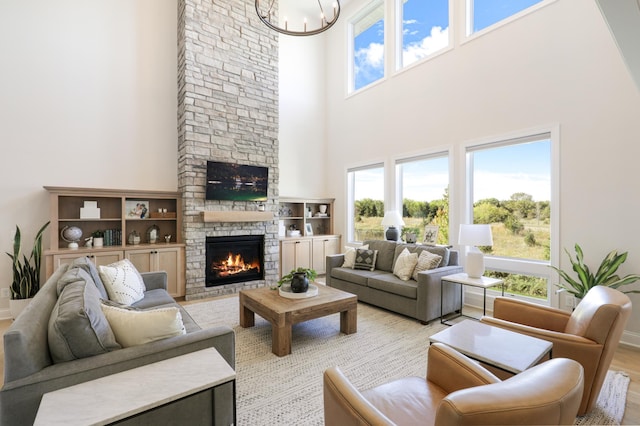 living room featuring a towering ceiling, a stone fireplace, and a healthy amount of sunlight