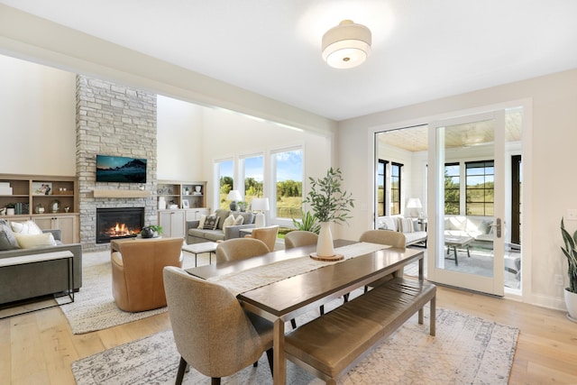 dining space with a stone fireplace and light wood-type flooring