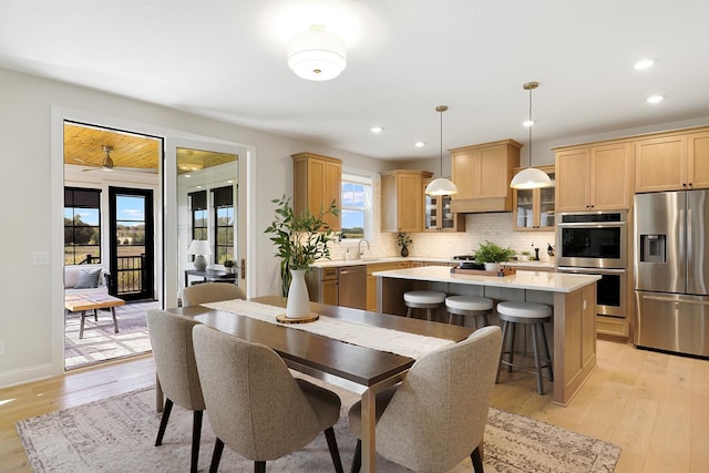 dining area with ceiling fan, light hardwood / wood-style flooring, and sink