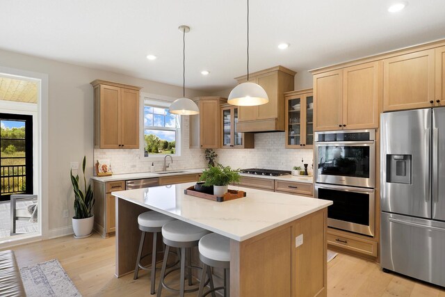 kitchen featuring light wood-type flooring, stainless steel appliances, pendant lighting, and a center island