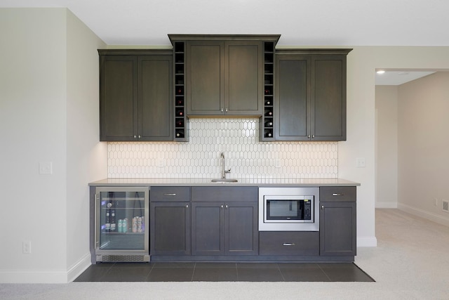 kitchen featuring stainless steel microwave, decorative backsplash, wine cooler, and sink