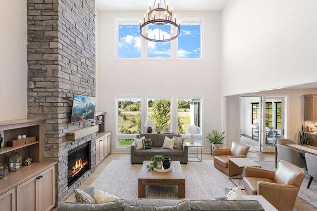 living room featuring a healthy amount of sunlight, a fireplace, a high ceiling, and a notable chandelier