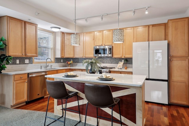 kitchen featuring dark hardwood / wood-style floors, stainless steel appliances, hanging light fixtures, and sink