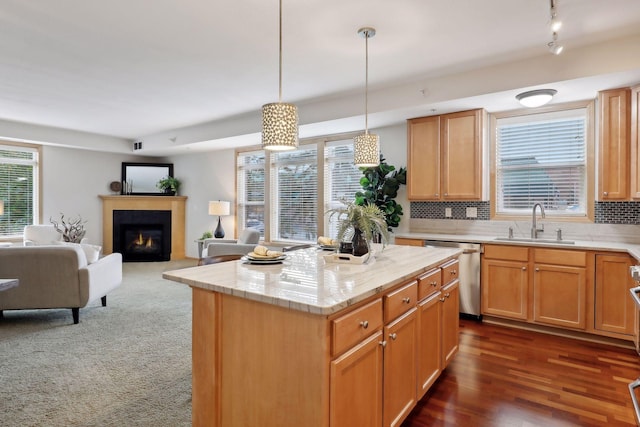 kitchen with dishwasher, backsplash, sink, hanging light fixtures, and a kitchen island