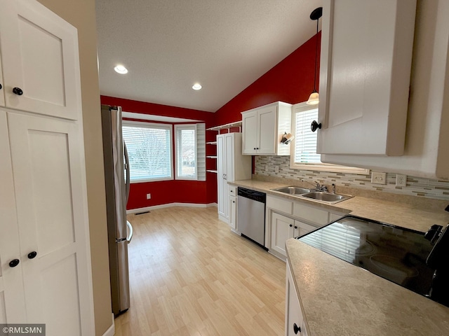 kitchen with white cabinetry, sink, hanging light fixtures, stainless steel appliances, and lofted ceiling