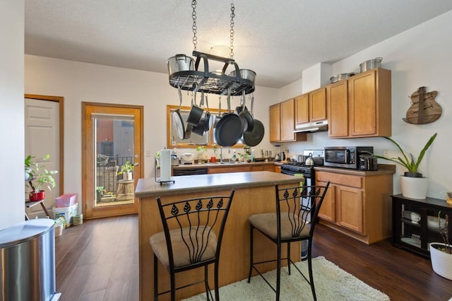 kitchen featuring dark hardwood / wood-style floors, a center island, a kitchen breakfast bar, and appliances with stainless steel finishes