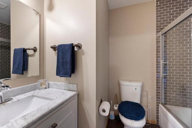 full bathroom with vanity, bath / shower combo with glass door, and toilet