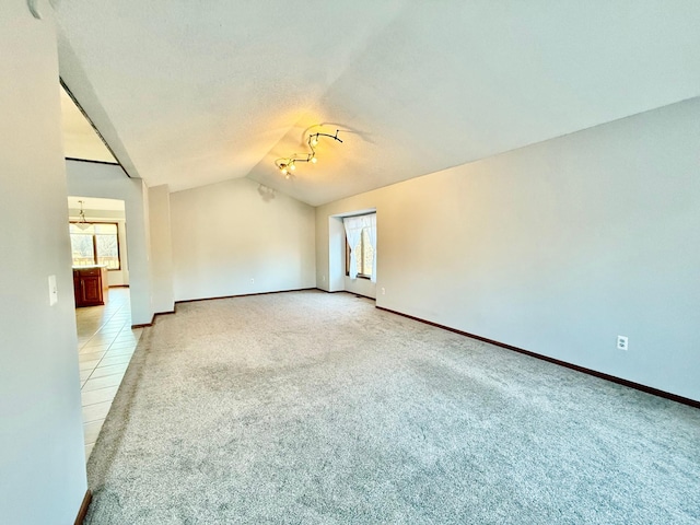 spare room with light colored carpet and lofted ceiling